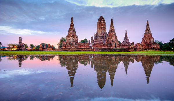 Temple d'Ayutthaya, Thaïlande, reflété dans l'eau au crépuscule avec un ciel nuageux pastel.